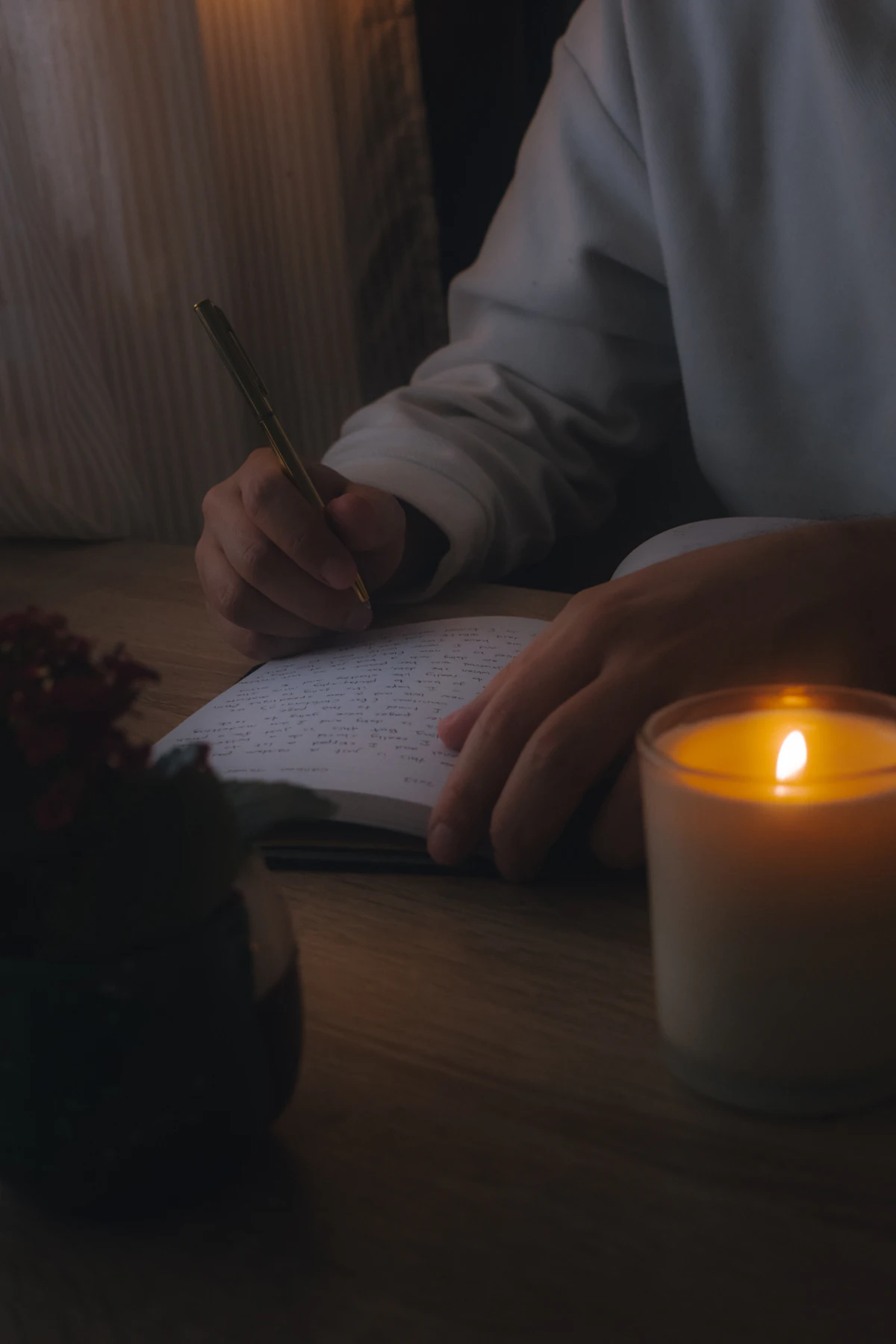 Persona escribiendo en un cuaderno a la luz de una vela
