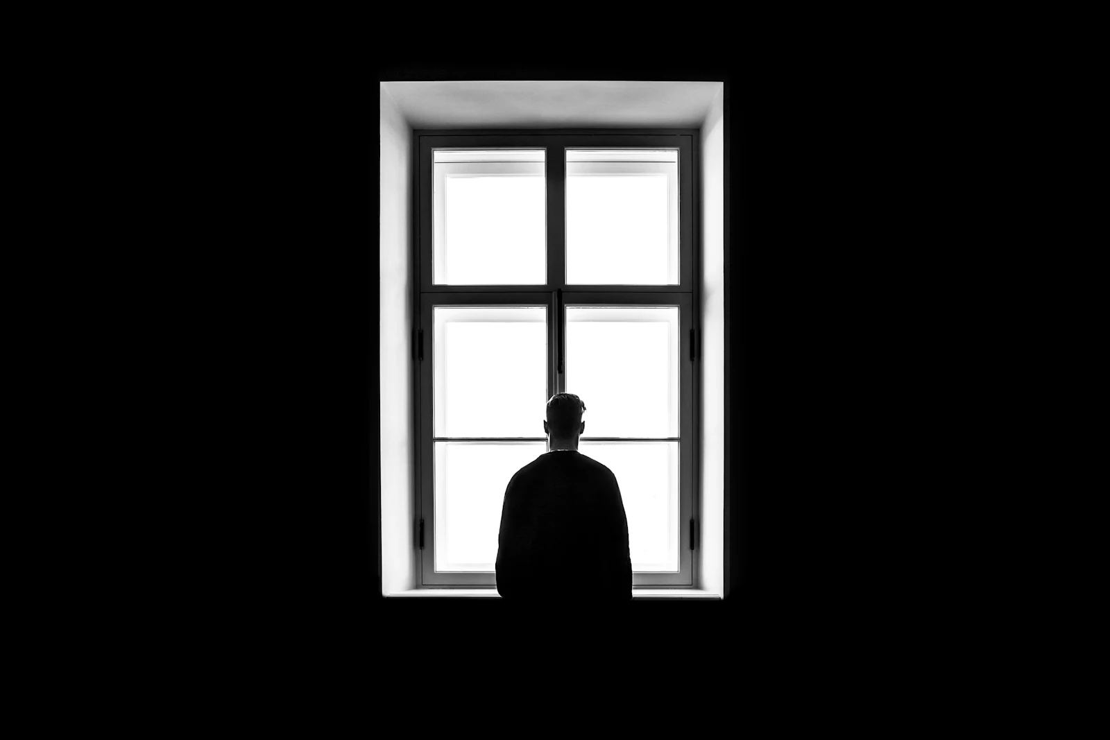 Silueta de una persona frente a una ventana iluminada